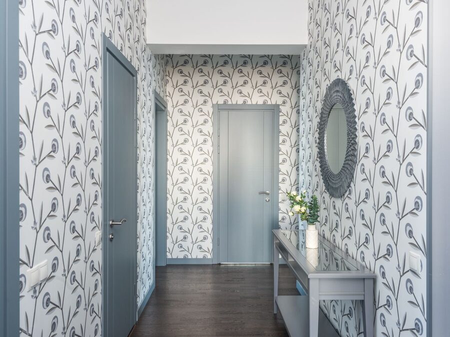 Hallway lined with delicate leaf-pattern wallpaper and a console table