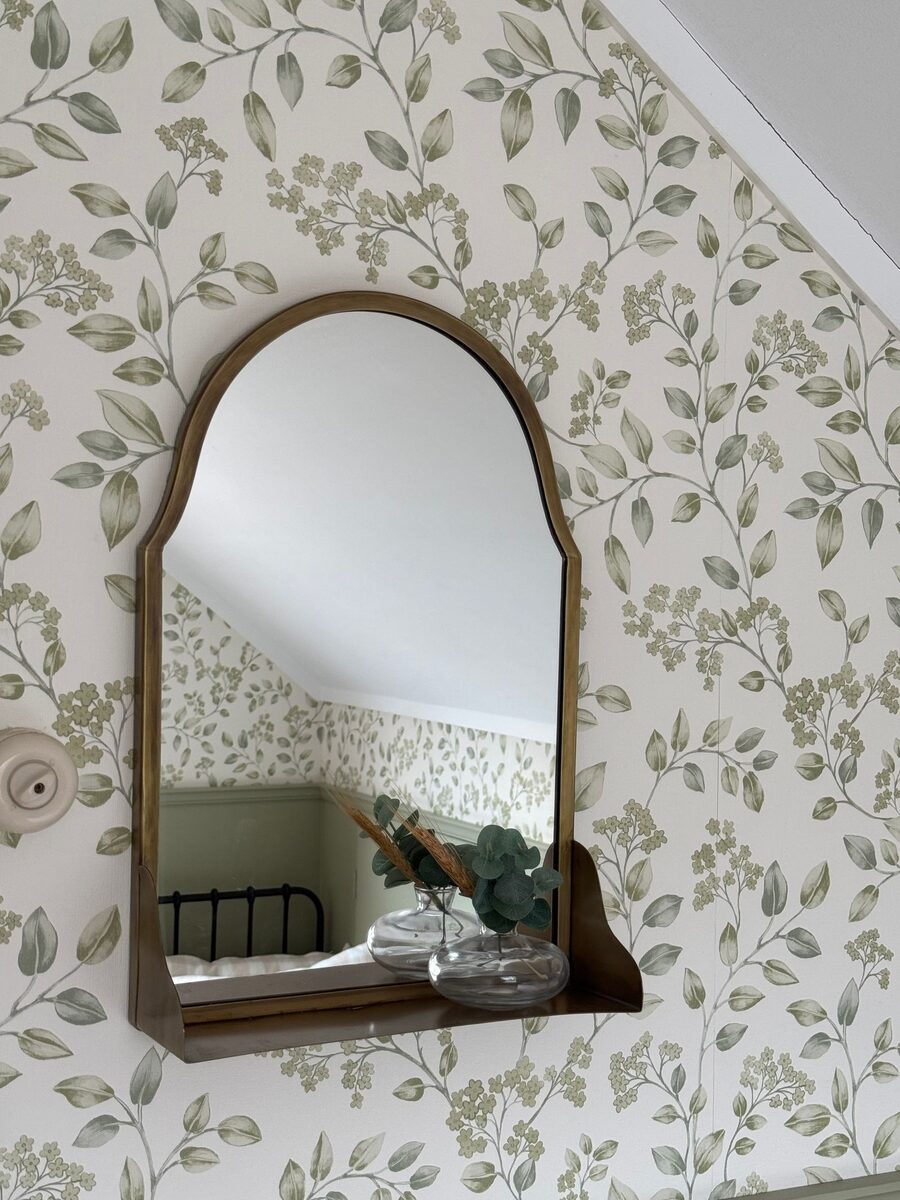 Botanical leaf wallpaper reflected in an arched mirror
