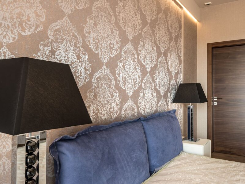 Bedroom with damask patterned wallpaper and bedside lamps